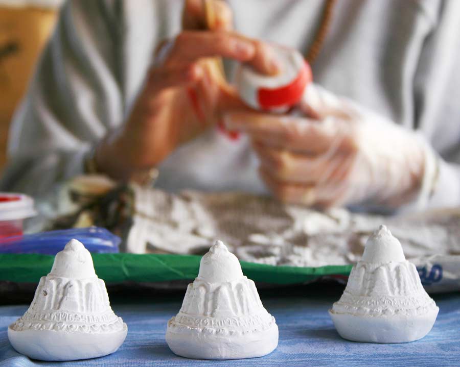 Painting tsa-tsa molds - small representations of a Stupa, filled with mantra and incense