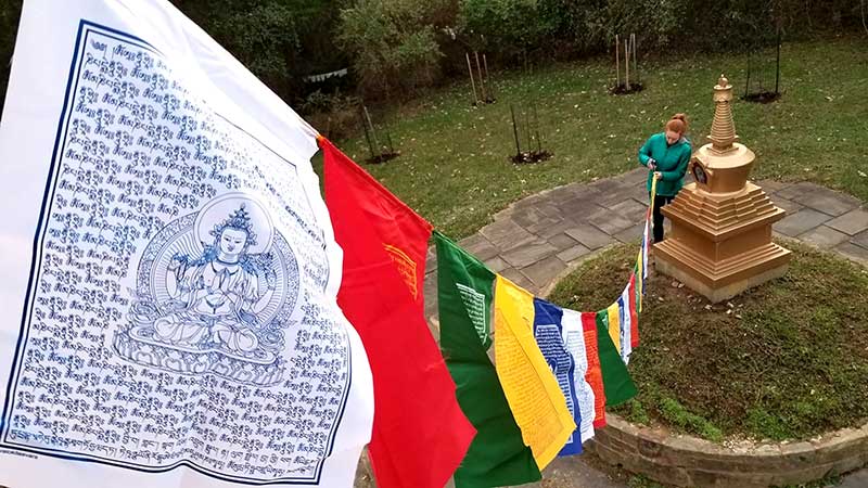 A volunteer hangs traditional Tibetan prayer flags in the long life stupa park at KPC Maryland