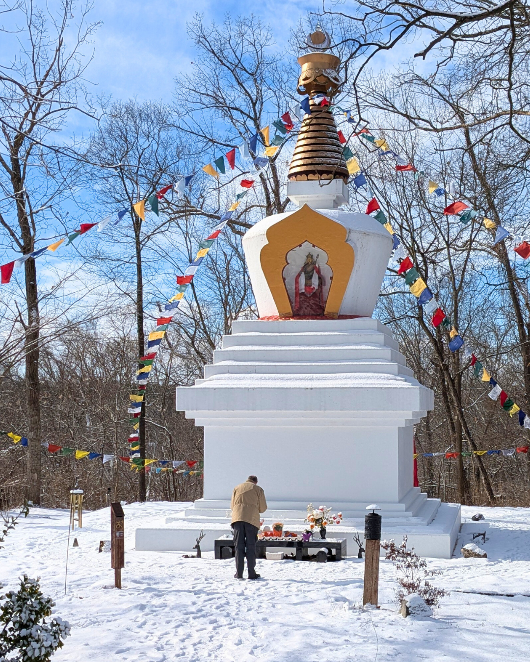 Man praying at the Enlightenment Stupa on a beautiful snowy day