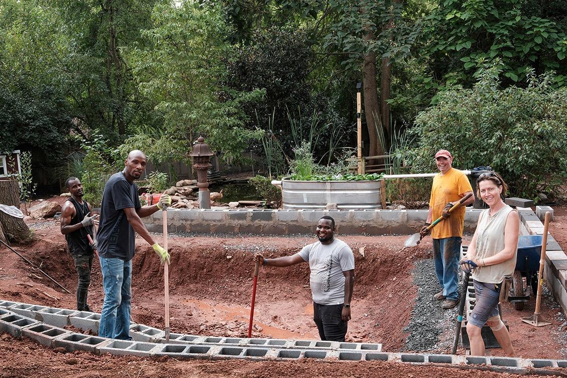 Pond workers with shovels, smiling at the camera